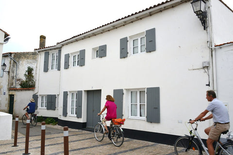 Everyday cyclists riding past whitewashed houses in Les Portes-en-Ré, Île de Ré